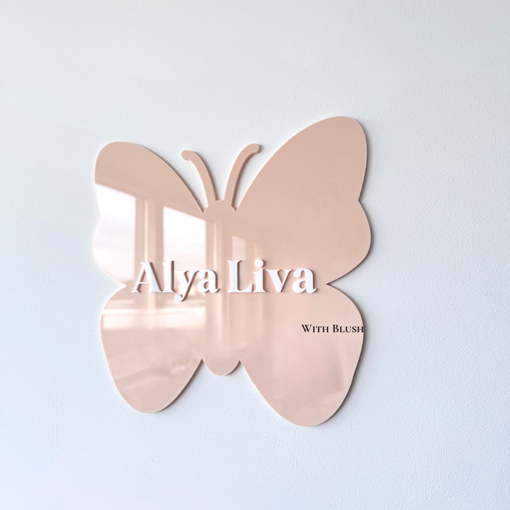 gepersonailseerde naambord in de vorm van een vlinder van gekleurd plexiglas in de kleur peach, met naam uitgesneden uit wit plexiglas.