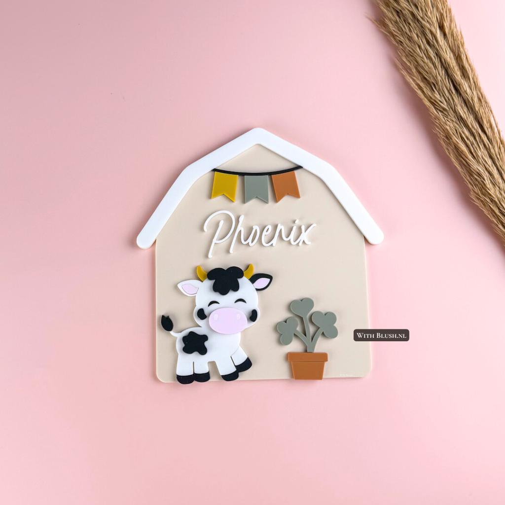 gepersonaliseerd naambord in de vorm van een schuur met een baby koe en plant en vlaggetjes van gekleurd plexiglas