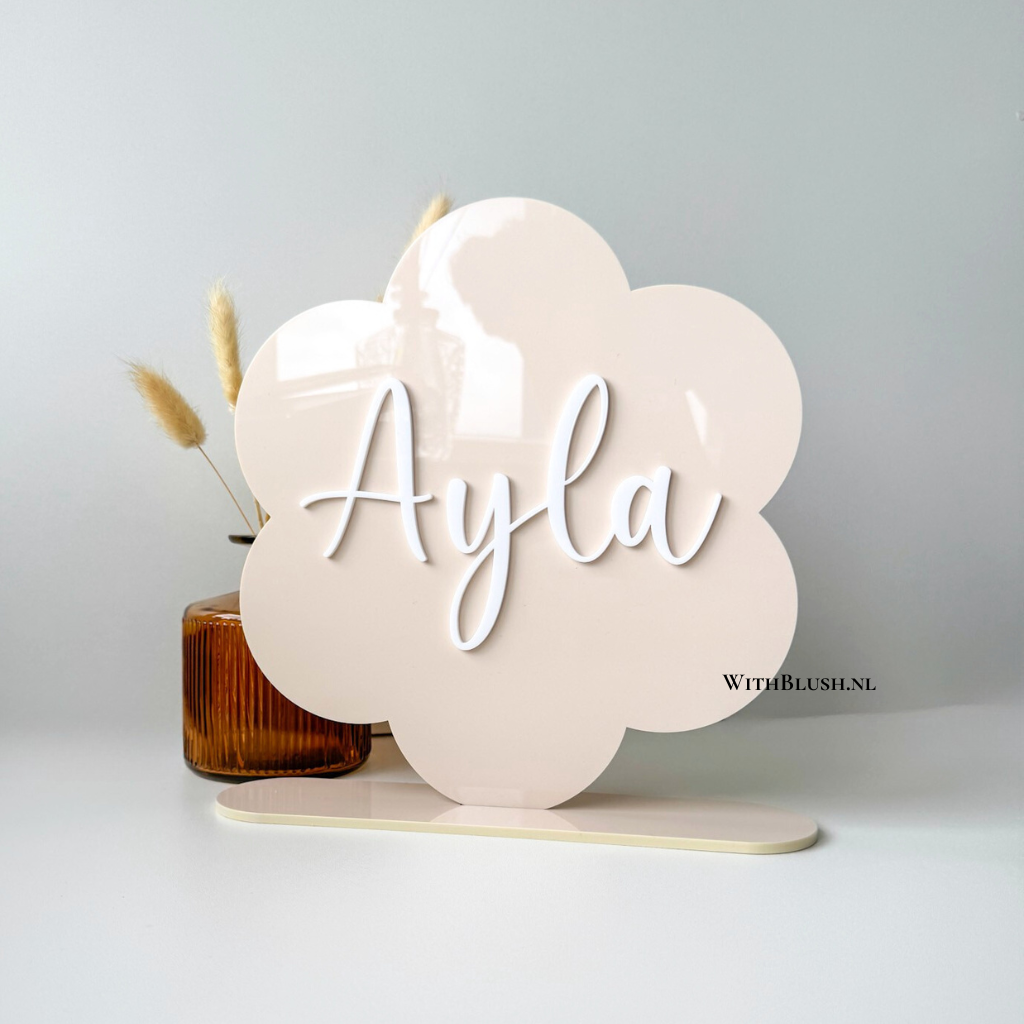 gepersonaliseerd naambord in de vorm van een madelief van gekleurd glanzend beige plexiglas en naam uitgesneden van wit glanzend plexiglas.