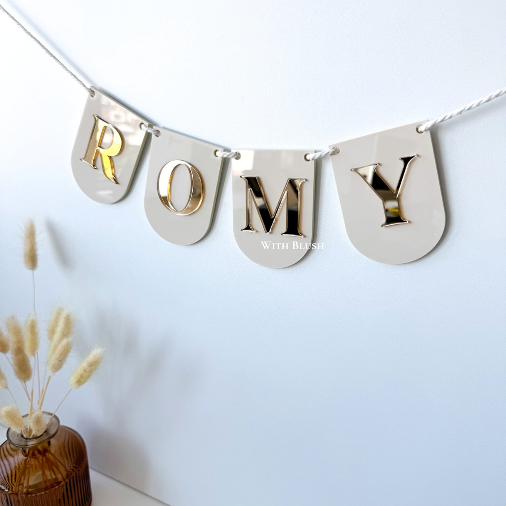 Decoratieve vlaggenlijn met naam Romy – Ronde vlaggetjes in beige glossy plexiglas, 3D letters in goud spiegelplexiglas. Perfect voor babykamers en feestdecoratie.