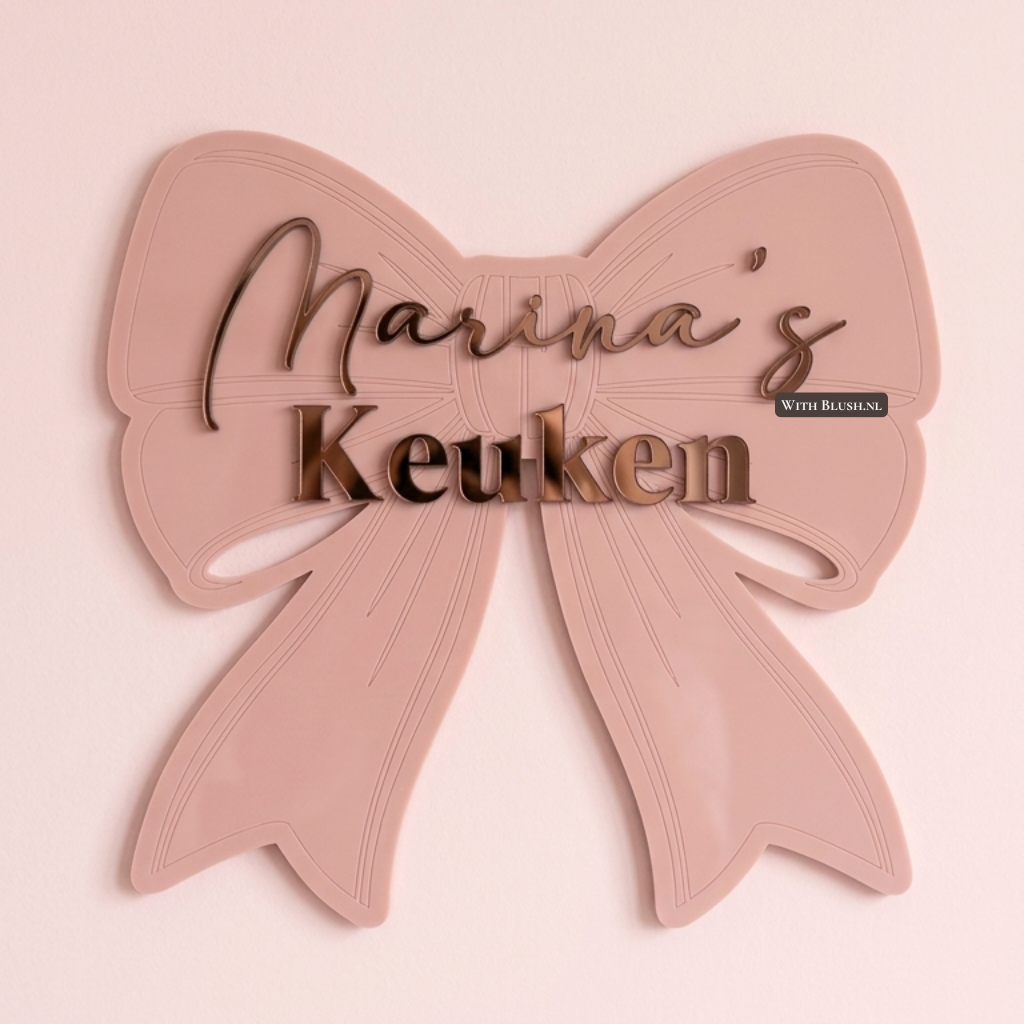 Wanddecoratie strik van roze acryl met de tekst Marina's Keuken in een combinatie van sierletters en blokletters in bronzen spiegel acryl.