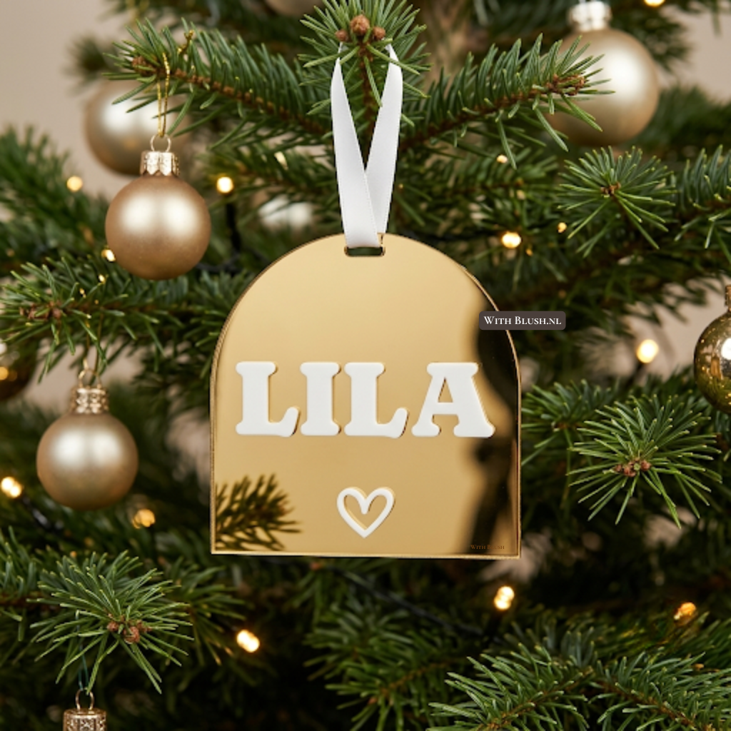 Gouden spiegel plexiglas kersthanger in boogvorm met een witte 3D naam en hartje, hangend in een versierde kerstboom met een witte satijnen lint.