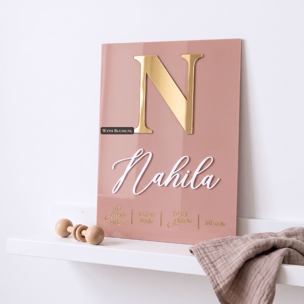 Oudroze gepersonaliseerd geboortebord van plexiglas met spiegelgouden 3D letter, witte 3D naam en goud gegraveerde geboortegegevens op een witte plank in de babykamer.