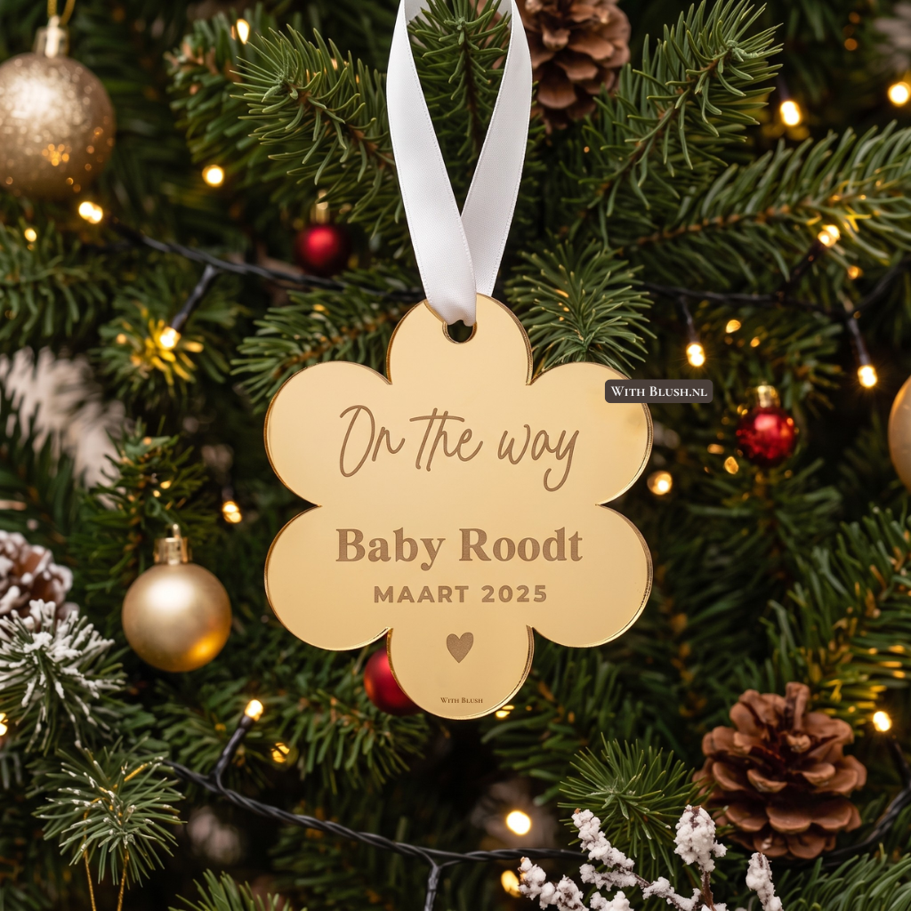 gouden spiegel plexiglas kerstornament voor een zwangerschapsaankondiging, hangend in een sfeervol verlichte kerstboom aan een wit satijnen lint. In het ornament is de tekst "On the way Baby Roodt MAART 2025" en een klein hartje aan de achterkant gegraveerd, wat een subtiel effect geeft.