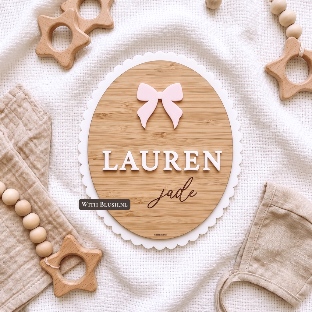 gepersonaliseerd ovaal houten baby naambordje op een witte doek. Het bordje heeft een bamboe middenstuk met een witte schulprand van acryl plexiglas. De naam "LAUREN" staat in witte 3D letters, met daaronder "jade" gegraveerd in het materiaal.