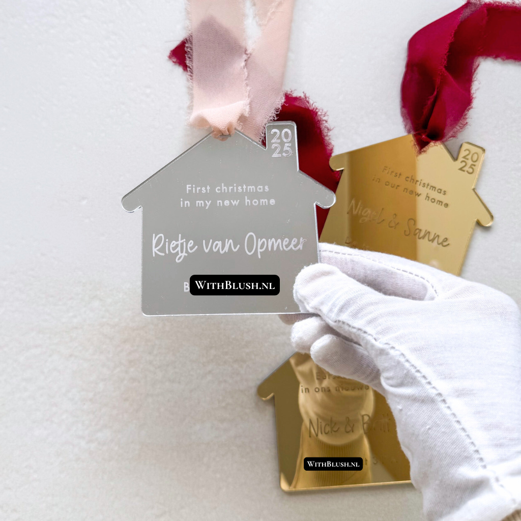 Kerstornament in huisvorm van silver mirror plexiglas met gegraveerde tekst “Eerste kerst in ons nieuwe huis”, namen en adres. Elegante, glanzende afwerking met koel zilvere spiegelreflectie. Wordt geleverd met ophangtouw — een stijlvol en persoonlijk cadeau voor de feestdagen.