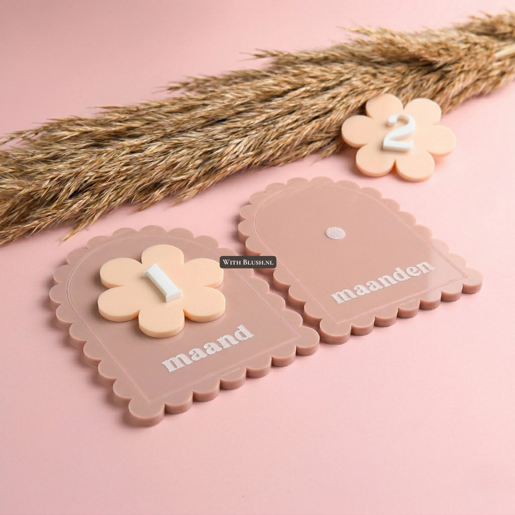 Luxe boogvormige oudroze acryl mijlpaalkaarten set voor baby's, een perfect gepersonaliseerd kraamcadeau. De kaarten hebben geschulpte randen en verwisselbare inzetstukken. De afbeelding toont '1 maand' met een bloem-inlegstuk en een lege kaart voor 'maanden'.