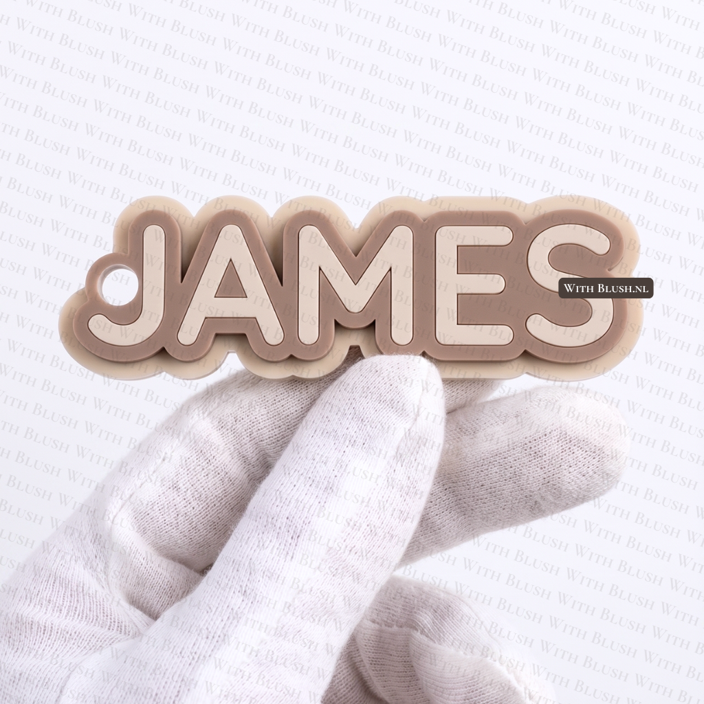 Gepersonaliseerde handgemaakte 3D sleutelhanger met de naam James in een gelaagde contourvorm van beige en cappuccino plexiglas.