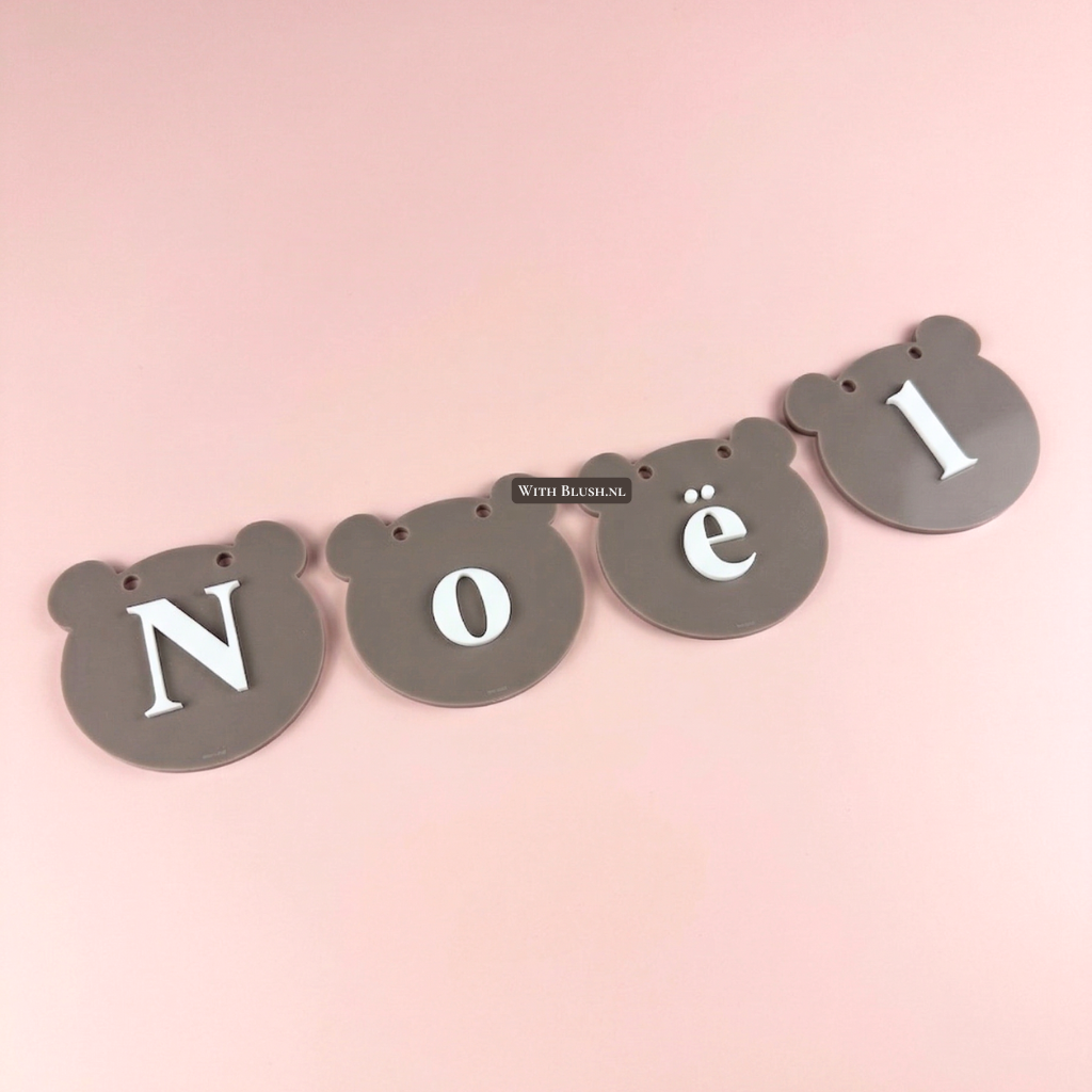 Gepersonaliseerde taupe bruine plexiglas naamslinger 'Noël' met vlaggetjes in de vorm van teddybeerkopjes en witte letters.